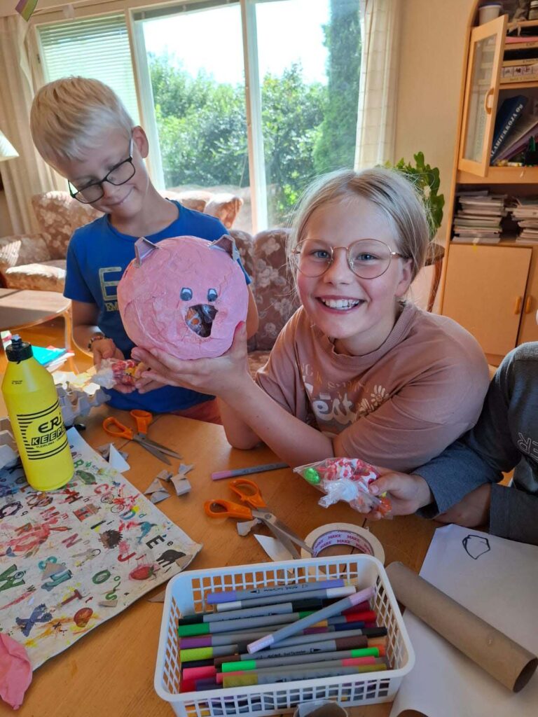 BILD: Ester visar upp en grispiñata som hon håller på och monterar ihop.